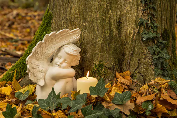 Engel mit Kerze auf einem Waldfriedhof Engel mit Kerze auf einem Waldfriedhof als Symbolbild für die Friedwald Bestattung
